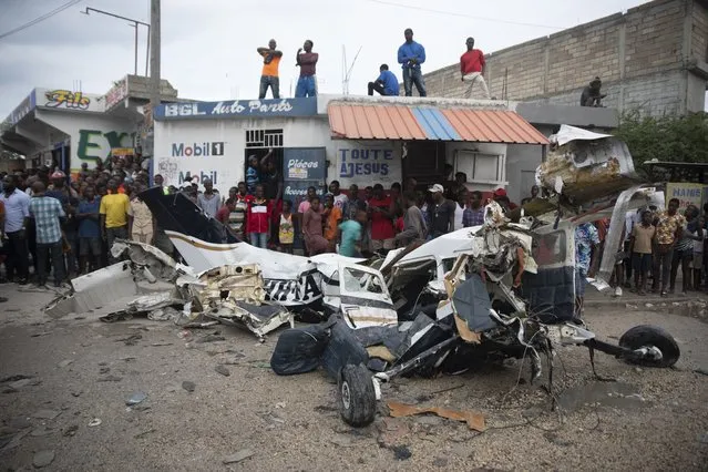 Onlookers mill around the wreckage of a small plane that crashed in the community of Carrefour, Port-au-Prince, Haiti, Wednesday, April 20, 2022. Police report that the plane was headed to the southern coastal city of Jacmel when it tried to land in Carrefour and that at least 5 people died in the accident. (Photo by Joseph Odelyn/AP Photo)