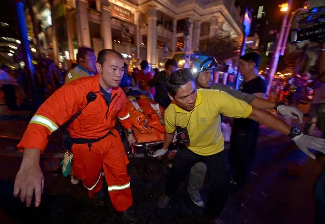 Thai rescue workers carry an injured person after a bomb exploded outside a religious shrine in central Bangkok late on August 17, 2015 killing at least 10 people and wounding scores more.  Body parts were scattered across the street after the explosion outside the Erawan Shrine in the downtown Chidlom district of the Thai capital. (Photo by Pornchai Kittiwongsakul/AFP Photo)