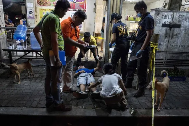 Police officers work the scene where an alleged drug dealer was killed during a police anti-drug operation in Manila on August 17, 2017. Police in the Philippine capital shot dead 25 drug suspects in another round of anti-drug raids, authorities said on August 17, as they followed President Rodrigo Duterte's call for dozens of deaths a day. The killings, carried out in Manila from Wednesday to Thursday morning, came after police shot dead 32 drug suspects in the province neighbouring the capital early in the week in what was billed as a “shock and awe” operation against drug traffickers. (Photo by Noel Celis/AFP Photo)
