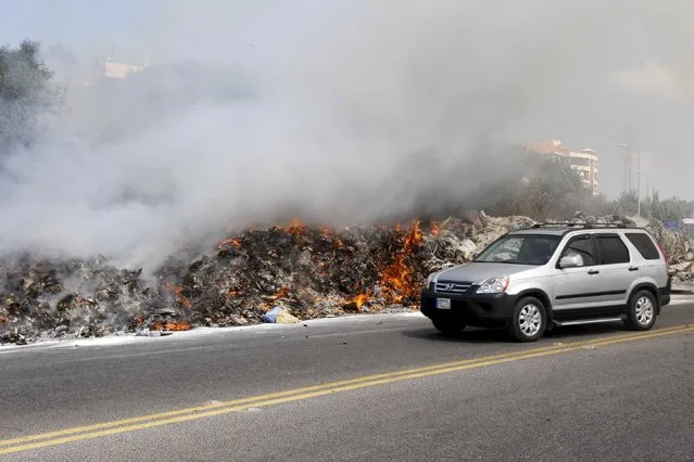 A car drives past burning garbage set on fire by residents, in Baabda near Beirut, Lebanon August 24, 2015. (Photo by Mohamed Azakir/Reuters)