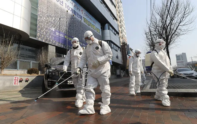 Workers wearing protective gears spray disinfectant against the new coronavirus in front of a church in Daegu, South Korea, Thursday, February 20, 2020. The mayor of the South Korean city of Daegu urged its 2.5 million people on Thursday to refrain from going outside as cases of the new virus spike. (Photo by Kim Jong-un/Yonhap via AP Photo)