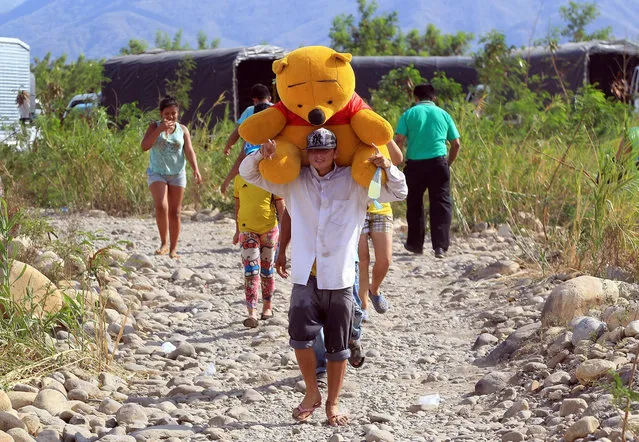 Colombian nationals carry their belongings across the Tachira river, from Venezuela to the La Parada area, close to Cucuta, Colombia, 25 August 2015. Colombian President Juan Manuel Santos asked the Venezuelan authorities to respect the Colombian people living in the border area and considered as “unacceptable” and “unbearable” the method used to deport them from Venezuelan territory. (Photo by Mauricio Duenas Castaneda/EPA)