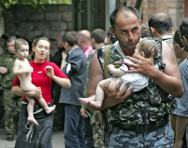 A soldier carries a baby and a woman follows him after the release of 26 women with their children in Beslan, North Ossetia, Thursday 02 September 2004. The first group of hostages were released after negotiation with the terrorists under the mediation of former president of Ingushetia Ruslan Aushev. (Photo by Sergei Chirikov/EPA)
