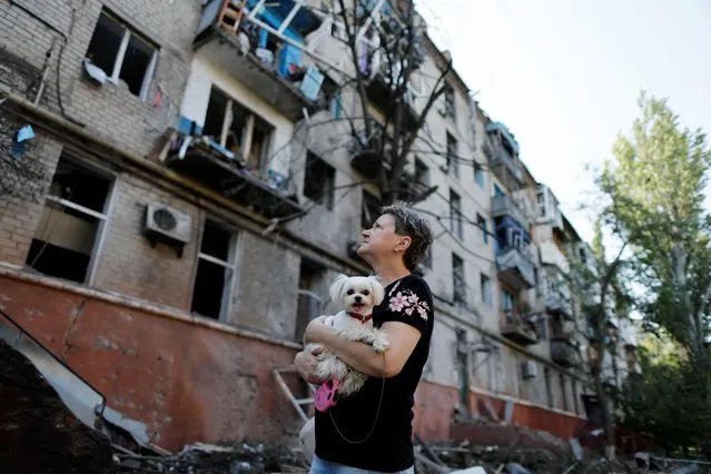 A Ukrainian woman holds a dog as she looks at a residential building damaged after a Russian strike, as Russia's attack on Ukraine continues, in Kramatorsk, Ukraine on August 31, 2022. (Photo by Ammar Awad/Reuters)