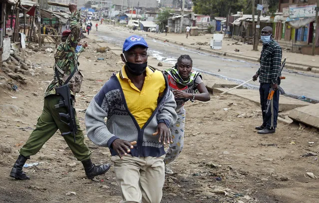 A woman who was returning home escapes after being beaten with a baton by police during clashes between protesters and police in the Kariobangi slum of Nairobi, Kenya Friday, May 8, 2020. (Photo by Brian Inganga/AP Photo)