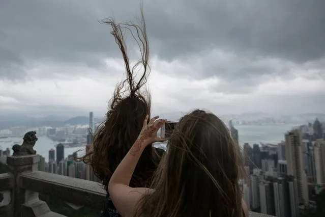 Tourists take photographs from a panoramic lookout on Victoria Peak during windy weather brought by typhoon Khanun in Hong Kong, China, 15 October 2017. (Photo by Erome Favre/EPA/EFE)
