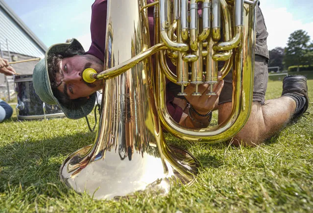 A competitor uses a brass instrument trumpet to lure worms as he takes part in the Falmouth Worm Charming Championships at the Dracaena Centre, on July 1, 2022 in Falmouth, Cornwall, United Kingdom. Worm charming is the act of enticing earthworms to the surface of the earth. Participants are allocated a 3x3m square zone in which to work, in teams of up to four people for a 30-minute period. Most worm charming methods involve vibrating the soil which encourages the worms to the surface. (Photo by Hugh R Hastings/Getty Images)