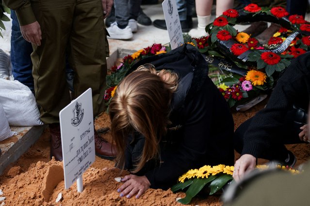 A woman touches a grave while relatives and friends mourn during the funeral for Israeli reserve soldier Sergeant major Gideon Ilani, who was killed during the ongoing ground operation by Israel's military against Palestinian Islamist group Hamas in the Gaza Strip, at the Mount Herzl military cemetery in Jerusalem on December 11, 2023. (Photo by Ronen Zvulun/Reuters)