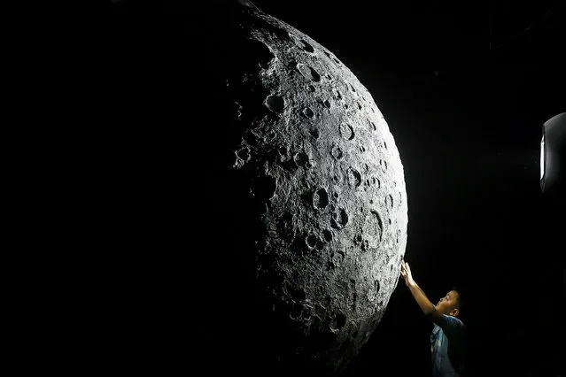 The boy touch to model of moon during Explore CASCI(China Aerospace Science and Cultural Innovation) ART Exhibition on October 2, 2022 in Wuhan, Hubei province, China. China is celebrating its 73nd National Day and a week-long holiday known as the “Golden Week”. (Photo by Getty Images）