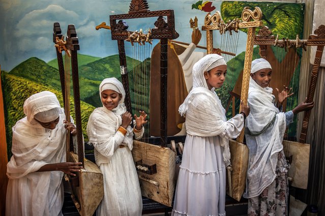 Young beginner students hold their begenas after a class practice session at Eman Begena School in Addis Ababa on February 13, 2025. The begena, a one-meter-long lyre with ten sheep-gut strings symbolizing the Ten Commandments, has been central to Ethiopian Orthodox prayers for centuries. Played seated and plucked with the left hand, begena players wear a netela, a traditional white garment. Once reserved for elites and later banned under the Derg regime, it has since seen a resurgence.Ermias Haylay has been key to its revival, founding a school seven years ago to train students globally. He also plays in retirement homes, hospitals, and during surgeries as musical therapy and runs a company producing and exporting begenas. With growing demand, he hopes to expand globally and explore its therapeutic effects. (Photo by Luis Tato/AFP Photo)