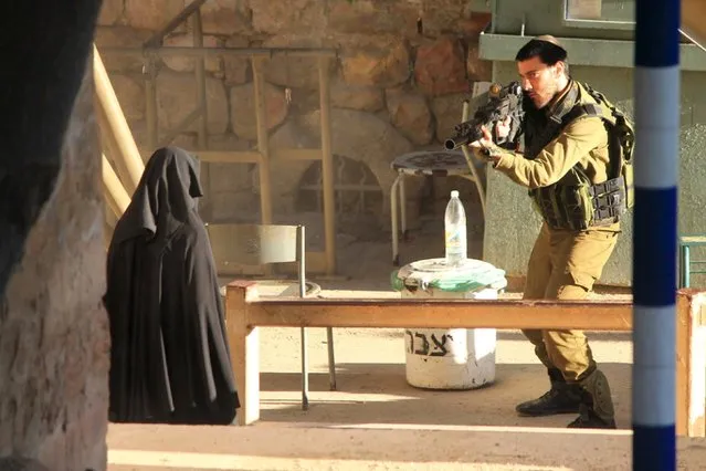 An Israeli soldier aims his rifle at a woman said to be 19-year-old Palestinian student Hadeel al-Hashlamun, before she was shot and killed by Israeli troops, at an Israeli checkpoint in the occupied West Bank city of Hebron September 22, 2015. The Israeli military said troops shot al-Hashlamun as she tried to stab a soldier. (Photo by Reuters/Youth Against Settlements Group)