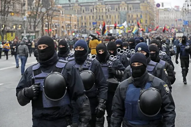 Ukrainian riot police walk in front of supporters of former Georgian President Mikheil Saakashvili during a protest march in Ukraine in Kiev, Ukraine, Sunday, December 10, 2017. From his jail cell in Ukraine's capital, opposition leader Mikheil Saakashvili is calling on supporters to rally for the impeachment of the president. (Photo by Sergei Grits/AP Photo)