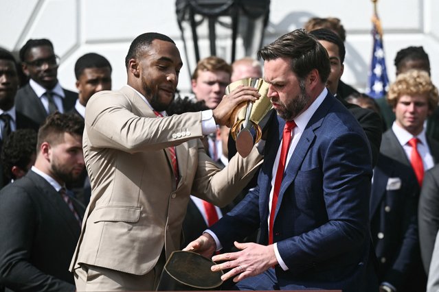 Running back TreVeyon Henderson (L) and US Vice President JD Vance bobble the College Football Playoff National Championship Trophy as US President Donald Trump hosts the 2025 College Football National Champions, Ohio State Buckeyes, celebrating the team's title-winning season with a ceremony on the South Lawn of the White House in Washington, DC, April 14, 2025. (Photo by Brendan Smialowski/AFP Photo)
