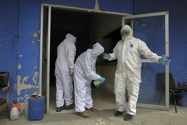 Workers spray each other with disinfectant solution after unloading the body of a person who died from suspected COVID-19, at the crematorium at Xilotepec Cemetery in Xochimilco, Mexico City, Monday, July 27, 2020. (Photo by Rebecca Blackwell/AP Photo)