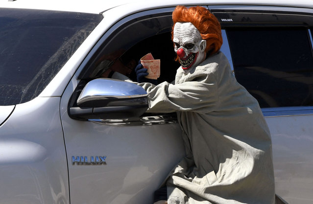 A reveler wears a mask to ask for money on a road as part of the holy week celebrations in Quimistan, Honduras on April 14, 2025. (Photo by Orlando Sierra/AFP Photo)