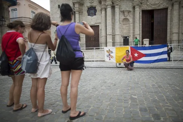 People take pictures with the Vatican (L) and Cuban flags in front of the The Cathedral of The Virgin Mary of the Immaculate Conception in Havana, September 18, 2015. (Photo by Alexandre Meneghini/Reuters)