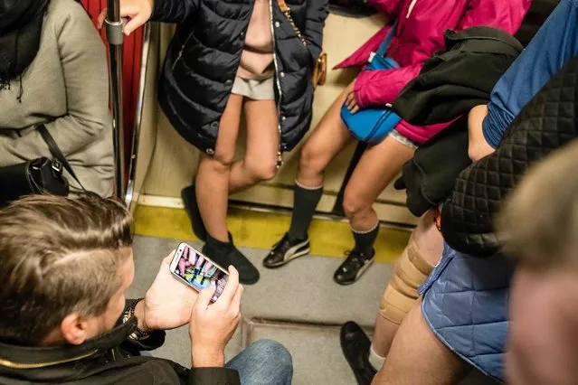 A passanger takes photos of people riding a subway train without pants during international No Pants Ride Day, Warsaw, January 7, 2018. The No Pants Subway Ride is an annual event which was started in 2002 by Improv Everywhere in New York, the goal is for riders to get on the subway train dressed in normal winter clothes without pants and stay serious. (Photo by Wojtek Radwanski/AFP Photo)