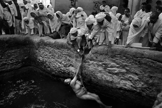 “Pilgrims gather to watch as an infertile worshiper is lowered into a baptism pool with a rope held by priests. According to local faith the holy water has fertility powers that will allow her to conceive. Every year, just before Christmas day, thousands of pious Christian orthodox worshipers make a pilgrimage to Lalibela, a small town in Ethiopia's highlands, known as Jerusalem of Africa or Black Jerusalem. Lalibela is famous for its 13th century monolithic churches, carved out of the living rock”. (Photo and comment by Gali Tibbon, Israel/2013 Sony World Photography Awards