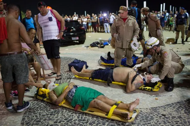 Firefighters give the first aid to people that were hurt after a car drove into the crowded seaside boardwalk along Copacabana beach in Rio de Janeiro, Brazil, Thursday, January 18, 2018. Military police said on Twitter that at least 11 people were injured and that the driver has been taken into custody. (Photo by Silvia Izquierdo/AP Photo)