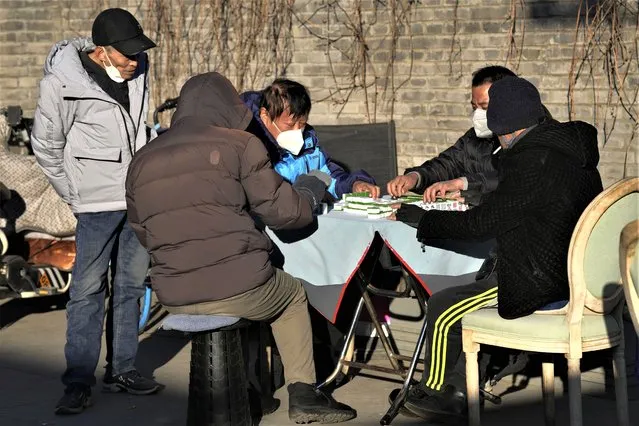 Residents wearing masks play mahjong outdoor during a sunny day in Beijing, Tuesday, December 27, 2022. (Photo by Ng Han Guan/AP Photo)