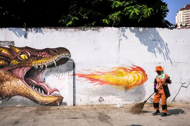A worker wearing a protective face mask, cleans up the road in front of a mural in Jakarta, Indonesia, 24 July 2020. Indonesian government has assigned a new team to rebuild the national economy amid the coronavirus pandemic. The country has started to ease COVID-19 lock-down restrictions in an effort to restart the economies and help people in their daily routines after the outbreak of coronavirus pandemic. (Photo by Mast Irham/EPA/EFE)