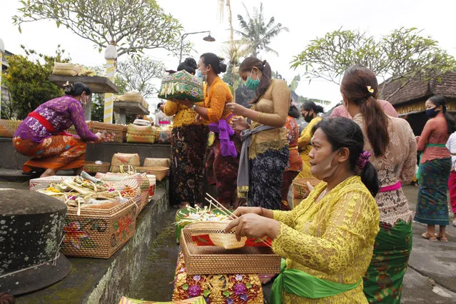 Women wearing face masks as a precaution against the new coronavirus outbreak participate in a Hindu ritual at a temple in Bali, Indonesia, Wednesday, September 16, 2020. (Photo by Firdia Lisnawati/AP Photo)