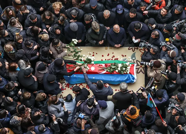 People gather around a coffin with the body of Orkhan Askerov, a security guard at Azerbaijan's embassy in Iran shot dead by a gunman in a recent attack, during a procession prior to a funeral in Baku, Azerbaijan on January 30, 2023. (Photo by Aziz Karimov/Reuters)