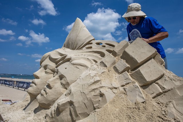 Slavian Borecki of Poland carves faces into his sculpture during the 21st annual Revere Beach International Sand Sculpting Festival at Revere Beach in Revere, Massachusetts on July 24, 2025. The theme for this year celebrates the 250th anniversary of the American Revolution and 15 master sculptors will compete for prizes. (Photo by Joseph Prezioso/AFP Photo)