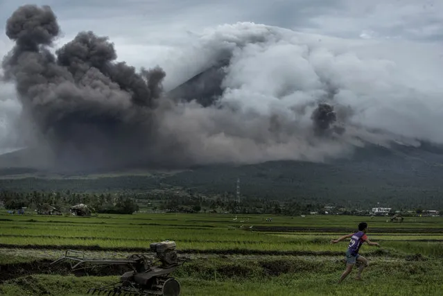 A boy runs as pyroclastic clouds emit from Mayon volcano on January 17, 2018 in Camalig, Philippines. Thousands evacuate as Philippines' Mayon volcano started to spew lava and ash as Philippine Volcanology Institute describes the event as a quiet eruption. Alert level 3 has been issued by authorities and warned that the activity could lead to eruptions of magma. (Photo by Jes Aznar/Getty Images)