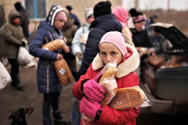 Anatasia, 10, holds loaves of bread given to her by a volunteer from a car, amid Russia's invasion of Ukraine, near Kherson, Ukraine on January 31, 2023. (Photo by Nacho Doce/Reuters)