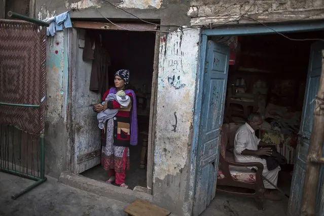 A woman carries her baby as she stands at the doorstep of her house at a Christian slum in Islamabad December 4, 2014. (Photo by Zohra Bensemra/Reuters)