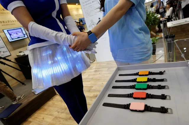 Women demonstrate Panasonic's Human Body Communication Device, which changed colour of LEDs on a cloth to same colour of wrist device at CEATEC (Combined Exhibition of Advanced Technologies) JAPAN 2016 at the Makuhari Messe in Chiba, Japan October 3, 2016. (Photo by Toru Hanai/Reuters)