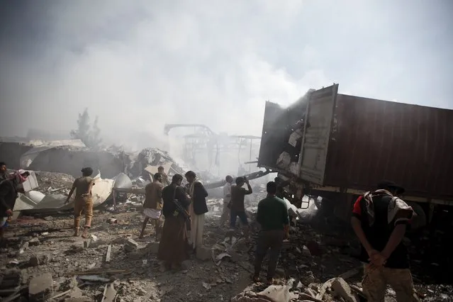 People stand at the site of a Saudi-led air strike that hit a food storage warehouse in Yemen's capital Sanaa October 25, 2015. (Photo by Khaled Abdullah/Reuters)