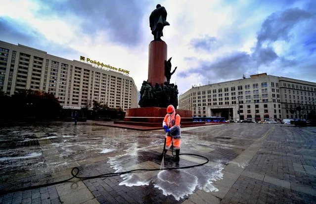 A municipal worker wearing a face mask and a protective suit to protect against the coronavirus disease disinfects a square near Lenin's monument in central Moscow on October 19, 2020. (Photo by Yuri Kadobnov/AFP Photo)