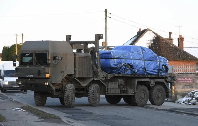 A vehicle wrapped in blue tarpaulin is removed from Larkhill Road in Durrington, 10 miles (16 kilometers) north of Salisbury, England, on the back of an Army lorry, Monday March 19, 2018, as the investigation into the suspected nerve agent attack on Russian double agent Sergei Skripal and his daughter Yulia continues. A road in the village of Durrington was closed off and tents were erected as the military and police searched for clues Monday. (Photo by Ben Birchall/PA Wire via AP Photo)