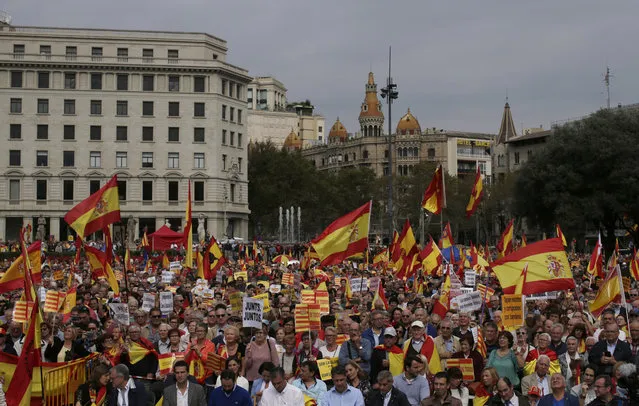 People hold banners and Spanish flags as they gather during the celebration for Spain's National Day in Barcelona, Spain, Wednesday, October 12, 2016. Thousands of Spaniards gathered in Barcelona on Wednesday to assert their right to be Spanish as well as Catalan in a protest designed to prove to separatists their position against splitting away from Spain. Catalan regional lawmakers recently approved to hold an independence referendum next September with or without agreement from Spain. (Photo by Manu Fernandez/AP Photo)
