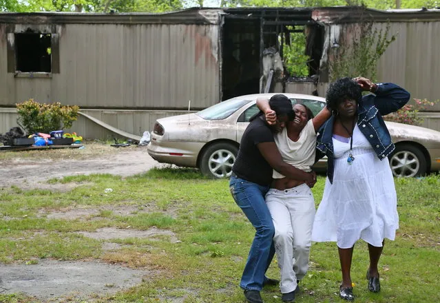 Leigh Hawkins, center, weeps for her four grandchildren who were killed in a fire at their mobile home the day before in Hartsville, S.C., Thursday, April 25, 2013.  Authorities say smoke inhalation killed 10-month-old twin sisters Myasia and Kynasia Hawkins and their brothers, 2-year-old Camaron Mason and 4-year-old Delonta Dixon. Hawkins daughter is the children's mother. (Photo by  Gavin Jackson/AP Photo/The Morning News)