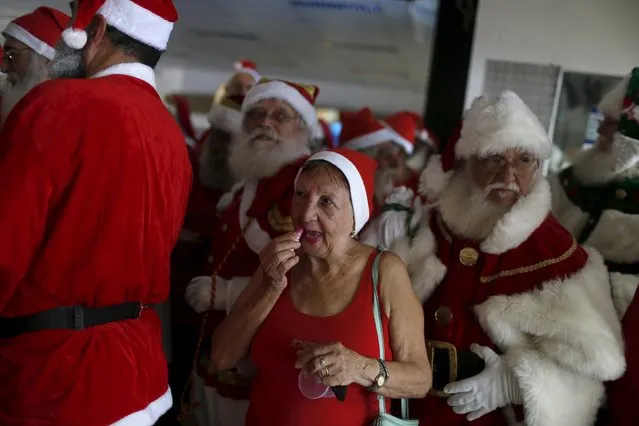 A woman uses a lipstick while accompanying students of the "Escola de Papai Noel do Brasil" (Brazil's school of Santa Claus) during the graduation ceremony in Rio de Janeiro, Brazil, November 10, 2015. (Photo by Pilar Olivares/Reuters)