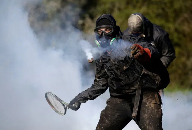 A protester uses a tennis racket to hit a tear gas cannister during the evacuation operation by French gendarmes in the zoned ZAD (Deferred Development Zone) at Notre-Dame-des-Landes, near Nantes, France, April 11, 2018. (Photo by Stephane Mahe/Reuters)