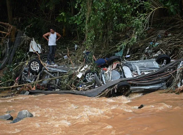 People try to rescue items from cars destroyed by a flash flood in Petropolis, Brazil on February 16, 2022. At least 55 people were killed in devastating flash floods and landslides that hit the picturesque Brazilian city of Petropolis, turning streets into torrential rivers and sweeping away houses, officials said Wednesday. (Photo by Carl De Souza/AFP Photo)