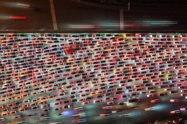 Drivers merge onto expressway lanes after passing through the Wuzhuang toll station at Chuzhou, in China's eastern Anhui province, as they make their way back home on the second-to-last day of an eight-day National Day holiday on October 7, 2025. The Wuzhuang toll station, located on the border between Anhui and Jiangsu provinces, is China's largest expressway toll station, with a total of 36 lanes. (Photo by AFP Photo/China Stringer Network)