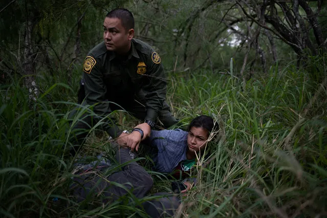 A border patrol agent apprehends a woman and a man after they were caught illegally crossing into the U.S. border from Mexico near McAllen, Texas, U.S., May 2, 2018. (Photo by Adrees Latif/Reuters)
