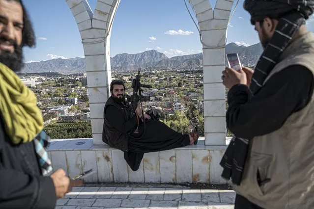 A Taliban security personnel take pictures of his colleague using a mobile phone at the Wazir Akbar Khan hilltop overlooking the Kabul city on April 4, 2023. (Photo by Wakil Kohsar/AFP Photo)