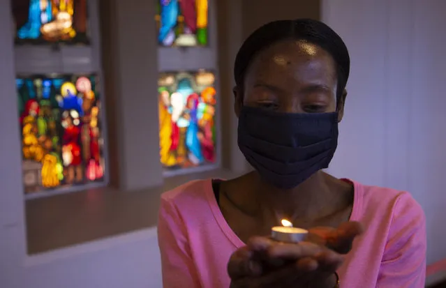 A worshipper wearing a face mask, holds a lit candle prior to a morning Christmas Mass at the Rosebank Catholic Church in Johannesburg, Friday, December 25, 2020. (Photo by Denis Farrell/AP Photo)