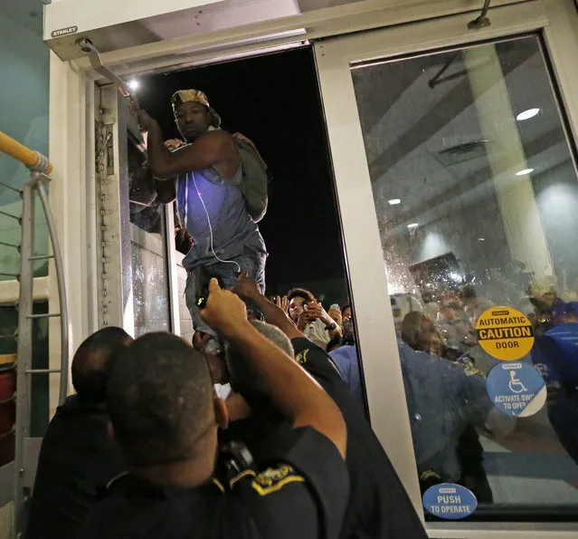 A police officer, front, points a taser as a protester jumps on a door, whole police officers try to keep out protesters against the former Ku Klux Klan leader and current senate candidate David Duke, before a debate for Louisiana candidates for the U.S. Senate, at Dillard University in New Orleans, Wednesday, November 2, 2016. The top five candidates, including Duke, who are running for Louisiana's soon-to-be-vacant U.S. Senate seat are meeting for their last debate ahead of next week's election, at the historically black university. (Photo by Gerald Herbert/AP Photo)