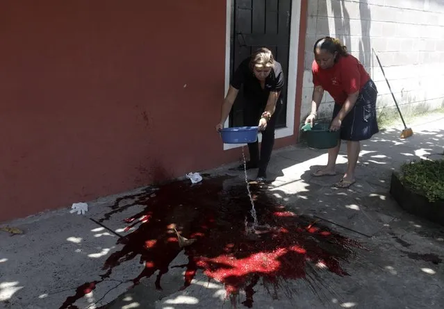 Women wash the blood off a sidewalk where a taxi driver had been killed by alleged gang members in Cuscatancingo October 2, 2014. (Photo by Jose Cabezas/Reuters)
