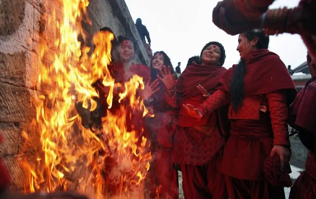 Nepalese women devotees stand around a bonfire to warm themselves warm after they take a holy dip in the Bagmati River during month long Swasthani Bratakatha festival in Kathmandu, Nepal, Tuesday, January 20, 2015. (Photo by Niranjan Shrestha/AP Photo)