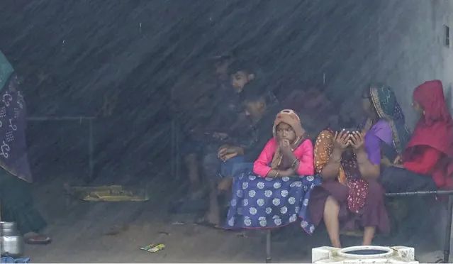 This screen grab made from AFPTV video footage taken on June 16, 2023 shows a family taking shelter in an abandoned shop in the coastal town of Mandvi as cyclone Biparjoy makes landfall. Cyclone Biparjoy tore down power poles and uprooted trees on June 16 after pummelling the Indian coastline, though the storm was weaker than feared and there were no immediate reports of casualties. (Photo by Shubham Koul/AFP Photo) 