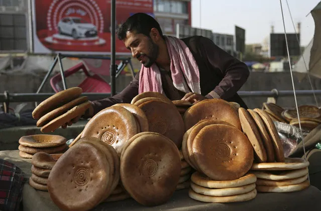 An Afghan street vendor sells bread before the Iftar meal that breaks the fast during the Muslim holy month of Ramadan, in Kabul, Afghanistan, Tuesday, June 5, 2018. Ramadan is marked by daily fasting from dawn to sunset and an increase of good deeds and charity. (Photo by Rahmat Gul/AP Photo)