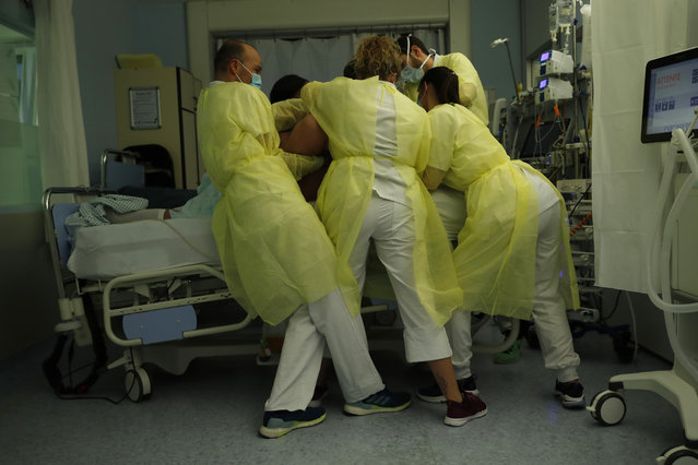 Nurse Anne-Catherine Charlier, right, and co-workers, wearing personal protection equipment, work in the intensive care ward for COVID-19 patients at the CHR Citadelle hospital in Liege, Belgium, Wednesday, December 16, 2020. Belgium has been hit hard by the pandemic with more than 18,000 confirmed deaths. The patient was not confirmed but suspected to have coronavirus. (Photo by Francisco Seco/AP Photo)